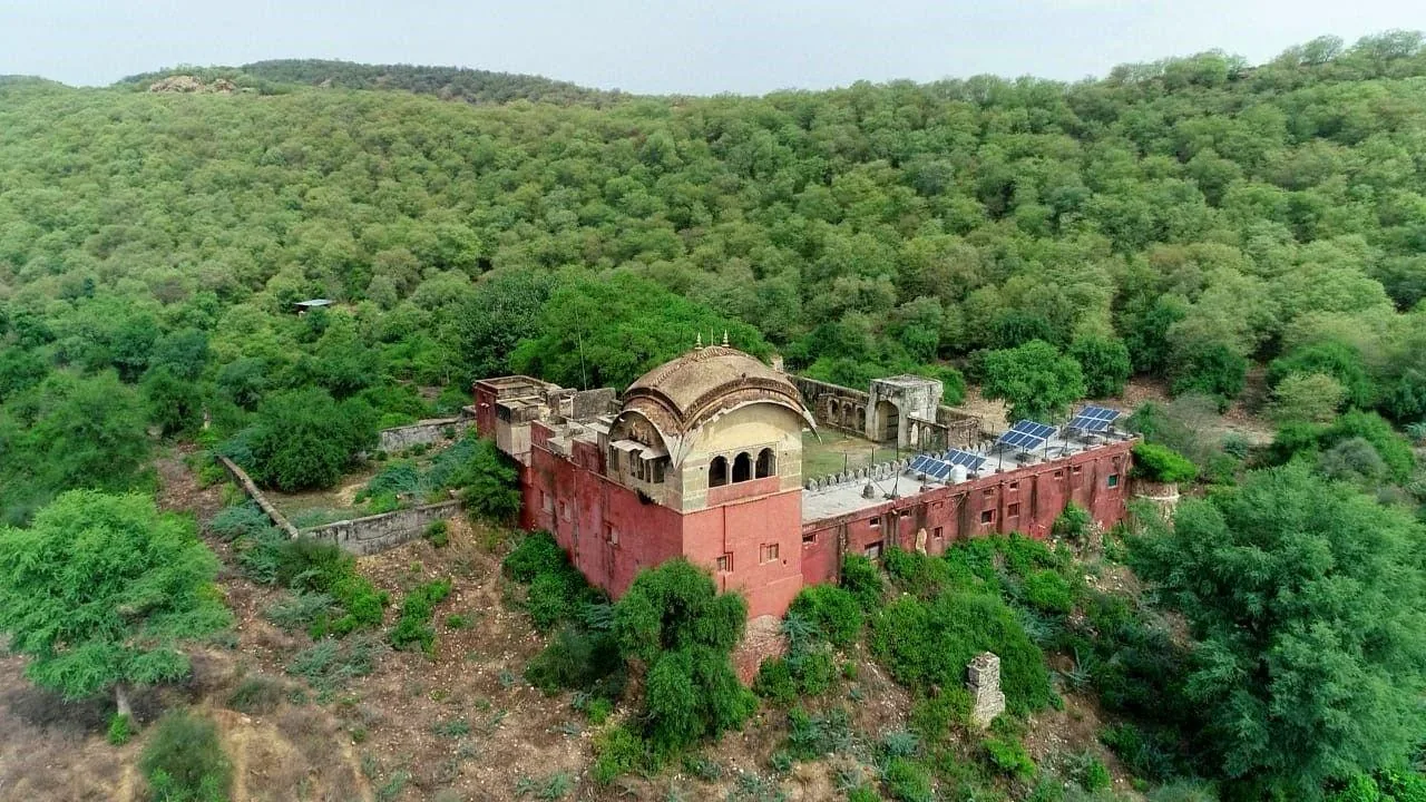 Aerial view of a historic fort with solar panels, surrounded by dense forest